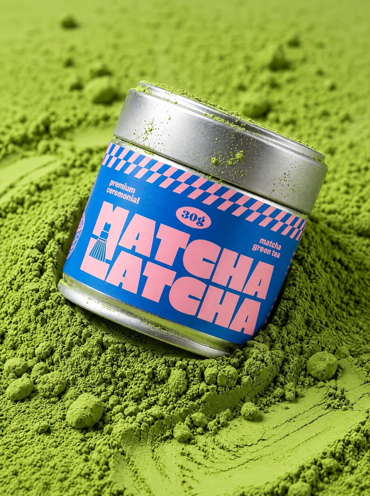 Plechovka Matcha Latcha zabořená v hromadě zářivě zeleného matcha prášku
