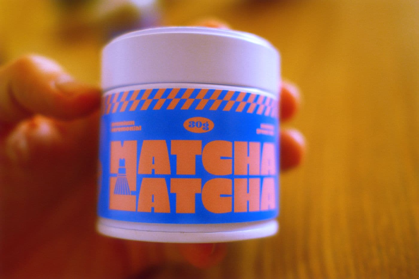 Plechovka Matcha Latcha v ruce při západu slunce